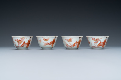 Four Chinese iron-red and gilt cups and saucers with figures near a table, Kangxi