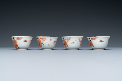 Four Chinese iron-red and gilt cups and saucers with figures near a table, Kangxi