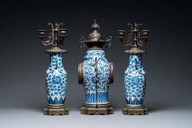Een Chinese met brons gemonteerde driedelige klokgarnituur met blauw-witte vazen, 19e eeuw