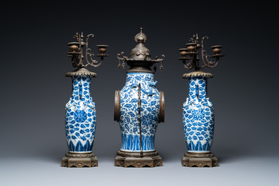 Een Chinese met brons gemonteerde driedelige klokgarnituur met blauw-witte vazen, 19e eeuw