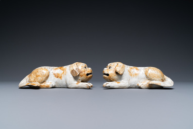 A pair of Chinese porcelain models of reclining dogs, Qianlong/Jiaqing