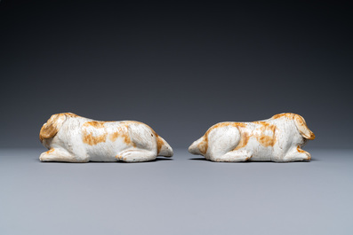 A pair of Chinese porcelain models of reclining dogs, Qianlong/Jiaqing