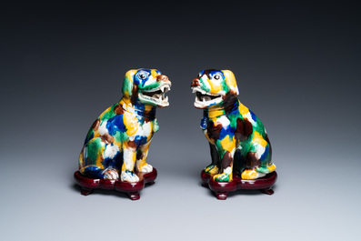A pair of Chinese sancai-glazed dogs on wooden stands, 19th C.