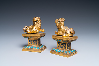 A pair of Chinese gilt bronze Buddhist lions on champlev&eacute; enamel bases, 18/19th C.