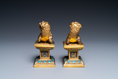 A pair of Chinese gilt bronze Buddhist lions on champlev&eacute; enamel bases, 18/19th C.