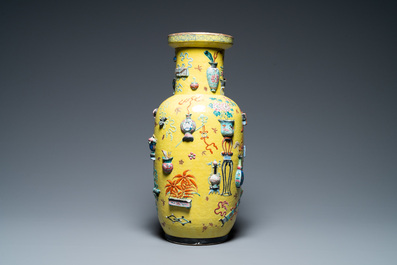 A Chinese yellow-ground famille rose rouleau vase with applied 'antiquities' design, 19th C.