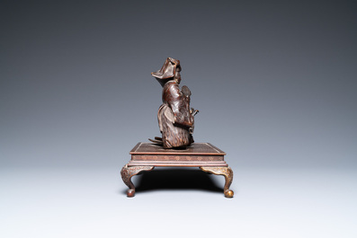 A Japanese bronze okimono depicting two figures on a base, Meiji, 19th C.