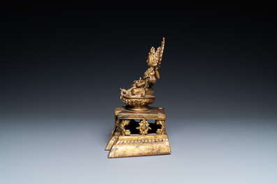 A Sino-Tibetan gilt bronze figure of Ushnishavijaya on a lotus throne with an inscription on the back, 18th C.