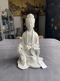 A Chinese Dehua blanc de Chine figure of Guanyin on a wooden stand, 19/20th C.