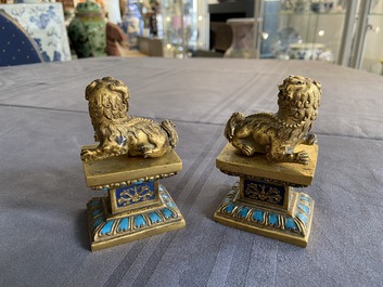 A pair of Chinese gilt bronze Buddhist lions on champlev&eacute; enamel bases, 18/19th C.