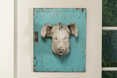 A white-patinated pig's head mounted on a turquoise-ground cabinet door, 20th C.