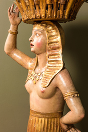 Een polychrome terracotta 'Egyptomanie' sculptuur van een Egyptische dame met bloemenmand, onleesb. gesign., gedat. 1881