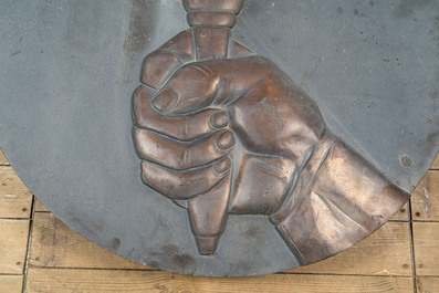 A patinated and partly gilt bronze Art Deco plaque with the hand of a bell-ringer, 20th C.