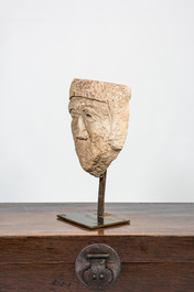 A large carved stone head of a winking man, 15th C. or later