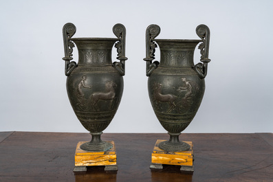 A pair of neoclassical style vases with charioteers on a Siena marble base, 19/20th C.