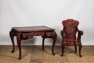 A finely carved Japanese red patinated wooden desk with armchair, 20th C.