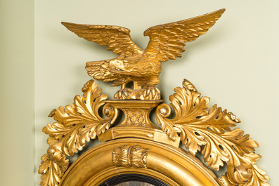 An impressive gilt wooden eagle-topped mirror with ebonised inner medallion, 19th C.