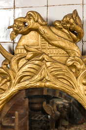 A gilt wooden mirror with floral design and crowned with a snake, 19th C.