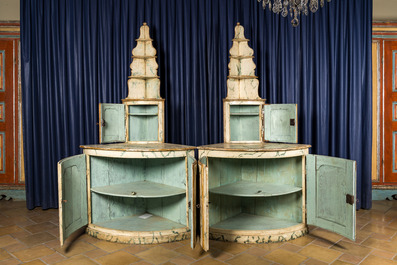 A pair of faux-marbre-painted wooden corner cupboards with a backdrop of shelves, France or Italy, 18/19th C.