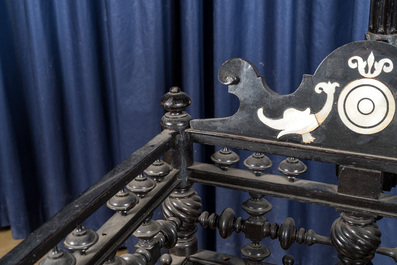 An attractive ebony-inlaid ebonised wooden cradle, 19th C.