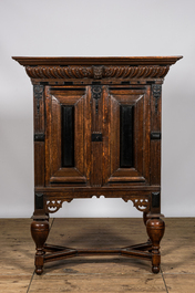 An oak and partly ebonised wooden two-door cupboard on foot, 19th C.