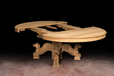 A bleached oak wooden oval table on a richly carved central base with dogs, 19th C.