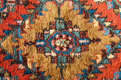 A long Oriental woolen runner with geometric motifs and floral design, 20th C.