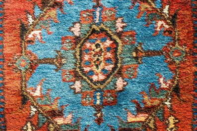 A long Oriental woolen runner with geometric motifs and floral design, 20th C.