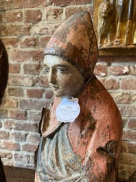 A Flemish carved and polychromed oak figure of a bishop on an armorial base, ca. 1500