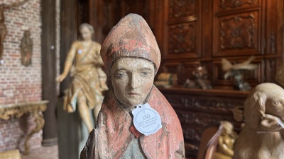 A Flemish carved and polychromed oak figure of a bishop on an armorial base, ca. 1500