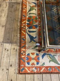 An Oriental woolen rug with floral design and geometric motifs, 20th C.