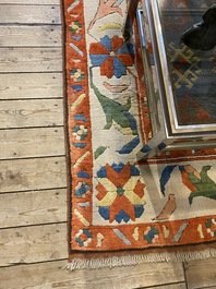 An Oriental woolen rug with floral design and geometric motifs, 20th C.