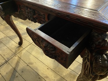 A finely carved Japanese red patinated wooden desk with armchair, 20th C.