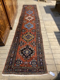 A long Oriental woolen runner with geometric motifs and floral design, 20th C.