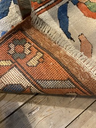 An Oriental woolen rug with floral design and geometric motifs, 20th C.