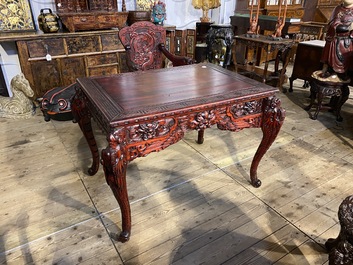 A finely carved Japanese red patinated wooden desk with armchair, 20th C.