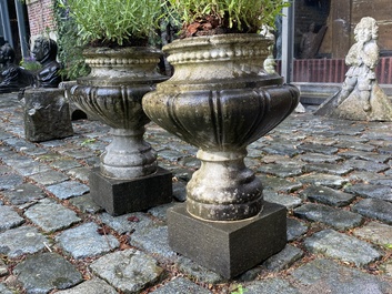 A pair of stone garden vases on square bases, one dated 1873