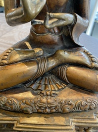 A large Tibetan brass and copper Buddha on throne, probably 16th C.