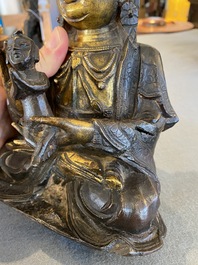 A Chinese partly gilt bronze Guanyin holding a boy, Ming