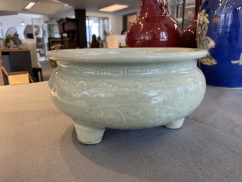 A Chinese celadon-glazed tripod censer with floral scrolls on wooden stand, Qing