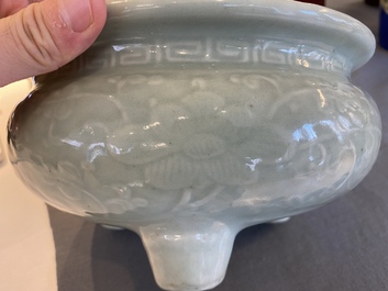 Een Chinese celadon-geglazuurde driepotige wierookbrander met florale slingers op houten voet, Qing