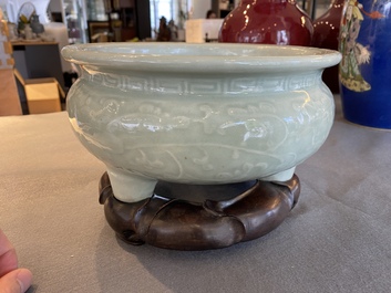 Een Chinese celadon-geglazuurde driepotige wierookbrander met florale slingers op houten voet, Qing