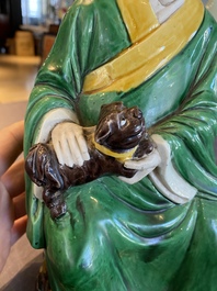 A Chinese verte biscuit figure of a Luohan holding a dog, probably Qing