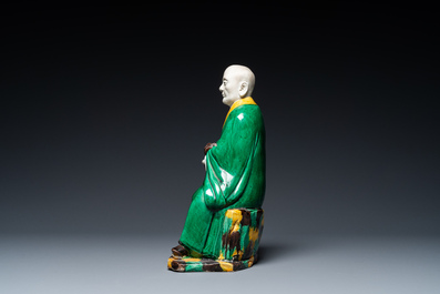 A Chinese verte biscuit figure of a Luohan holding a dog, probably Qing