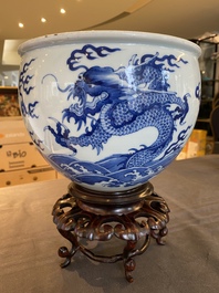 A Chinese blue and white 'dragons and carps' jardini&egrave;re on wooden stand, 19/20th C.