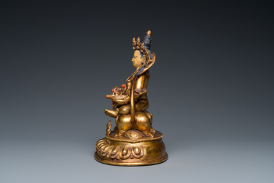 Een Tibetaanse vergulde bronzen groep van Jambhala op zijn leeuw, 19/20e eeuw