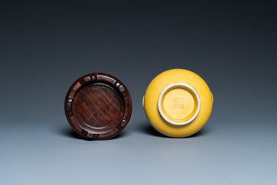 A Chinese monochrome yellow-glazed 'hu' vase on wooden stand, Qianlong mark, 19/20th C.