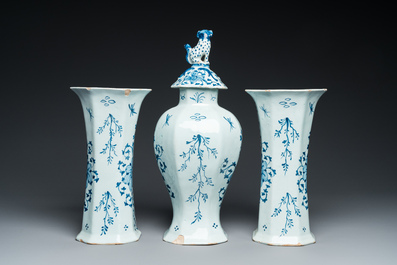 A Dutch Delft blue and white garniture of three vases with a large rose, 18th C.