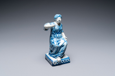 A polychrome Dutch Delft figure of a seated man and a blue and white one of a seated lady, 18th C.