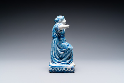 A polychrome Dutch Delft figure of a seated man and a blue and white one of a seated lady, 18th C.